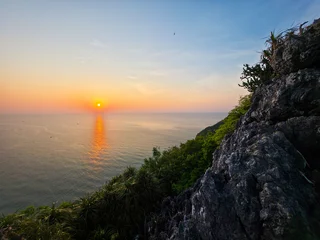 Fototapeten Küste Peaceful sunset over ocean horizon viewed from steep rocky cliff with lush green vegetation evoking serene and calm tranquil feeling in majestic beautiful nature environment setting  © CoreRock