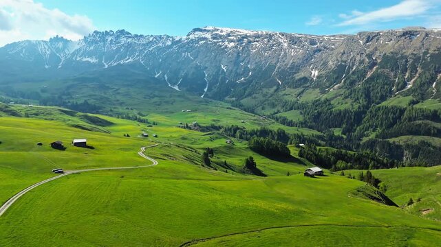Dolomites mountain landscape with alpine plateau of Alpe di Siusi, South Tyrol, Italy. Aerial view of green fields, roads and scattered huts