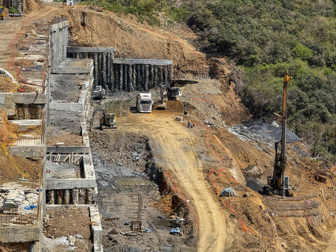 View of a large construction site with excavators, trucks, and a drilling rig working on a hillside with concrete retaining walls Sariyer, Istanbul, Turkey.