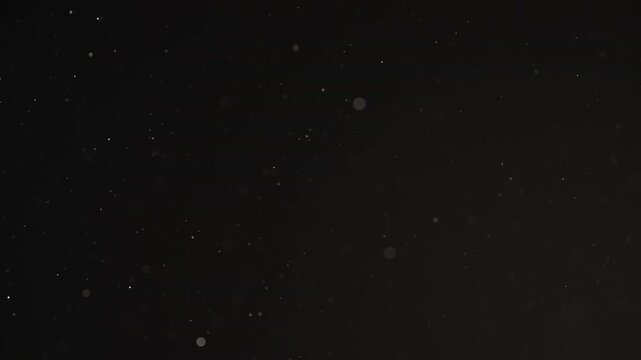 Slow motion real dust particles floating mid air over dark background