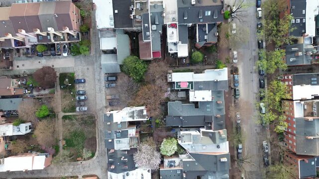 Residential spring grid blocks near S Paca St show mixed rooflines, narrow alleys, budding trees across dense residential rows. Varied shingles shape tight neighborhood textures Baltimore, MD