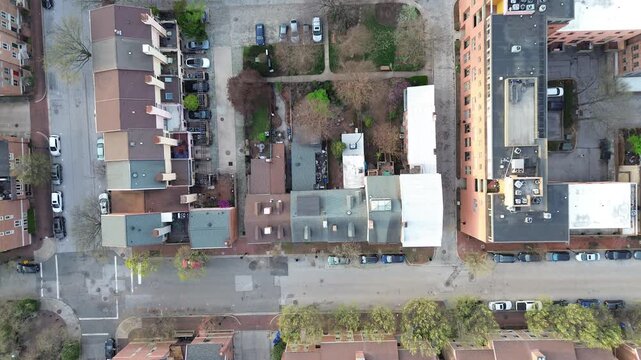 Courtyard residential grid blocks near S Paca St reveal mixed rooflines, parked vehicles, central courtyard with trees. Varied shingles, brick tones shape dense neighborhood textures Baltimore, MD