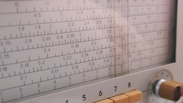 A vintage analog tuning dial displays precise numbers alongside a sliding vertical indicator. Concept of retro technology, scientific measurement, precision, and historical lab equipment.