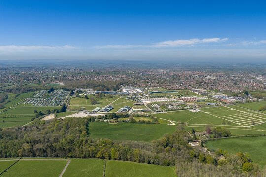 Drone view of the Harrogate Showground in North Yorkshire England featuring exhibition buildings parking areas green countryside and distant residential landscape beneath a sunny blue sky