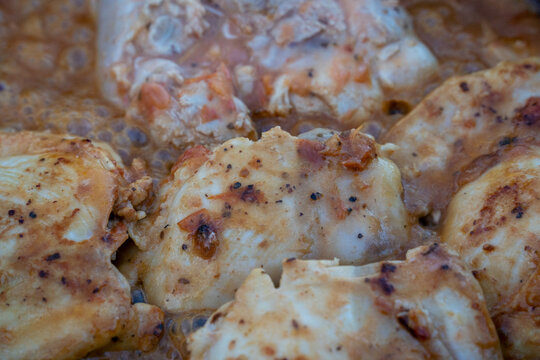 View of seasoned chicken pieces simmering in a bubbling tomato sauce in Moab, Utah, United States.