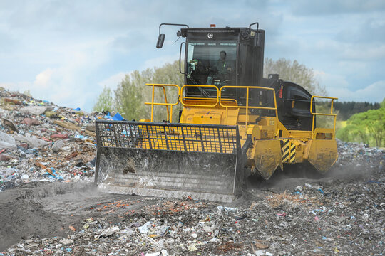 Heavy industrial machinery working at a large landfill site.  A view on a landfill compactor compacting and managing piles of waste.