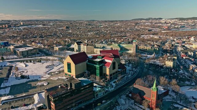 Aerial drone footage of The Rooms museum and art gallery building in St Johns NL with Basilica of St John the Baptist visible beside snowy city