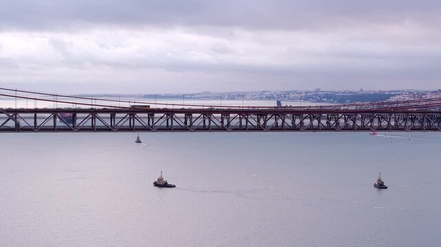 Ponte 25 de Abril rail and road bridge under an overcast sky on Tagus River estuary, Lisbon, Drone shot