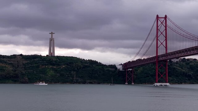 Ponte 25 de Abril suspension bridge on Tagus River estuary under an overcast sky, Sanctuary of Christ the King at a distance, Lisbon, Aerial