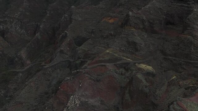 Moody drone flight deep inside a narrow, shadowed volcanic ravine in Santo Antao. The shot emphasizes the jagged textures and vertical scale of the island&rsquo;s ancient basalt rock formations
