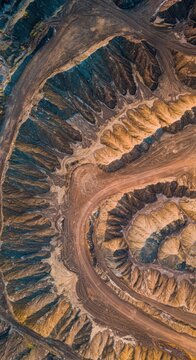 Abstract aerial view of heavily disturbed earth showing distinct geometric patterns and colors resulting from industrial excavation, aerial, mine, geology