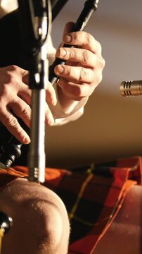Bagpipe player in a kilt plays musical instrument at the stage