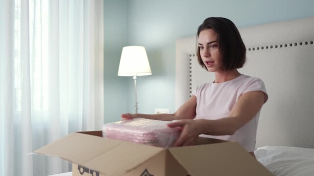 Content woman examining purchase from opened delivery box. Concept online retail and modern shopping.
