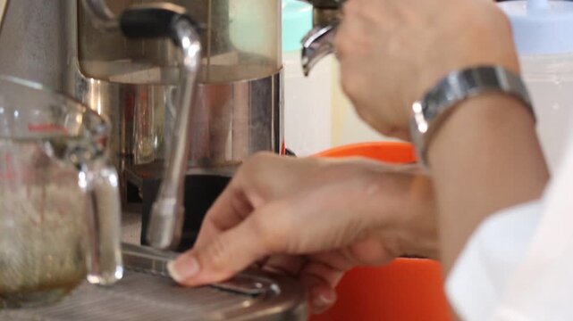 Barista Tapping Portafilter to Level Ground Coffee at an Espresso Machine Grinder
