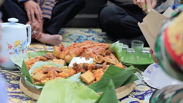 Close-up of people sharing Nasi Tumpeng, traditional Indonesian yellow rice platter. 4K culture video.