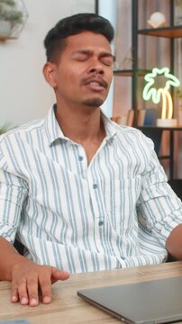 Indian man at home snaps laptop shut says enough and leans back exhales and promises break without apps. Arabian guy at desk rests hands behind head stares up and takes pause for mind reset and calm.