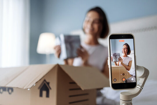 Female influencer recording product review on mobile phone. Concept social media marketing and consumer trends.
