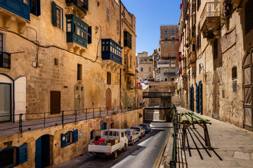 Traditional narrow street in Valletta with colorful wooden balconies and cars © Chris Jones