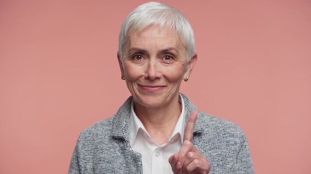 Senior Woman Giving Playful Warning Sign on Pink Background