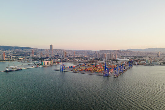 Drone view of cargo port infrastructure with container storage area and bulk terminal. Industrial waterfront and international shipping operations at sunset