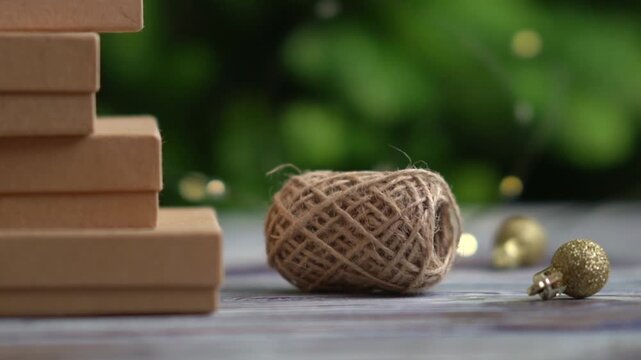 Holiday decor. Packing holiday gifts. Gift boxes and natural twine and Christmas gold balls on a Christmas tree background and bokeh