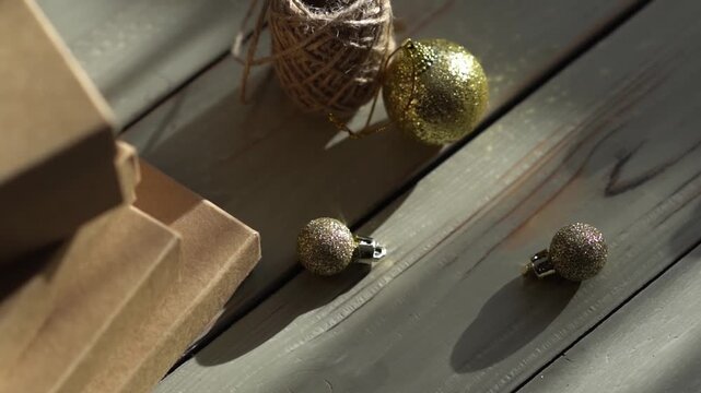 Holiday decor. Packing holiday gifts. Gift boxes, natural twine and Christmas gold balls on a wooden background.