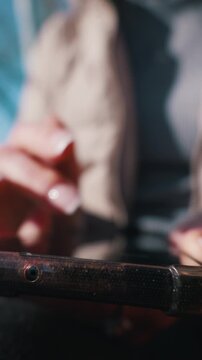 Smartphone user interacts with a touch screen in the background while the camera focuses on the device edge. Detailed textures of the mobile hardware are visible in a tight vertical macro.