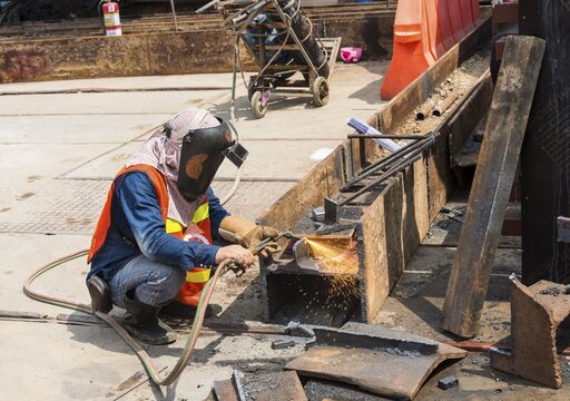 Construction worker welding a steel beam on a construction site, Bangkok, Thailand