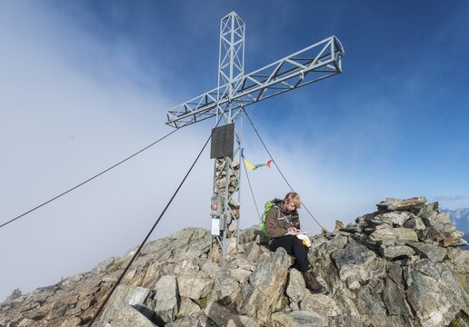 Hiker writing in the logbook at the summit, Greifenberg, 2618m, Rohrmoos-Untertal, Schladming Tauern, Styria, Austria