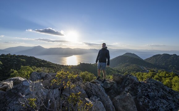 Hiker looking over volcanic peninsula Methana, view over sea and landscape with mountains and extinct volcanoes, Saronic Gulf, Peloponnese, Greece