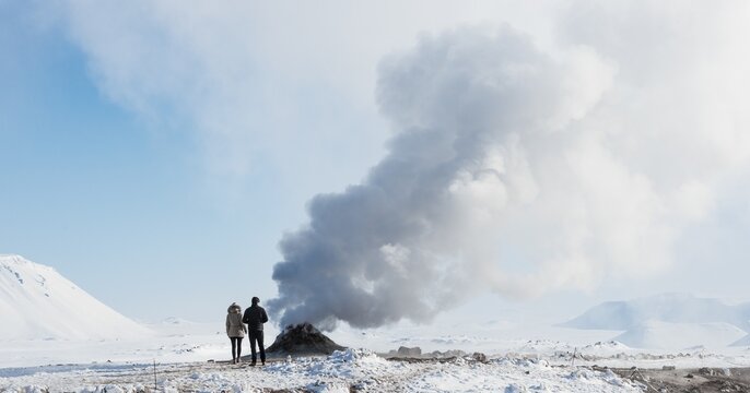 Two tourists standing beside steaming fumarole, solfatara in Hverar&ouml;nd, also Hverir or Namaskard, geothermal area, North Iceland, Iceland