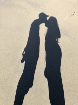 Shadows in the sand, couple kissing, sandy Bastendorff Beach, Oregon, USA