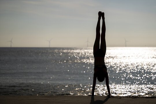 Girl doing a handstand by the sea, Silhouette, S&oslash;ndervig Strand, North Sea, Denmark