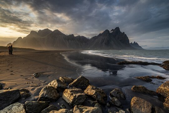 Two people standing on the beach, couple, adult, mountains, mountain range, sea, waves, surf, reflection, clouds, evening light, coast, summer, Vestrahorn, Stokksnes, H&ouml;fn, Iceland
