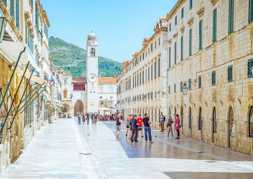 Dubrovnik, Croatia: People walking on a sunny street with a clock tower