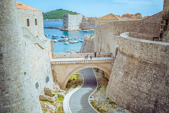 Dubrovnik, Croatia: Stone bridge and fortress walls overlooking harbor with boats