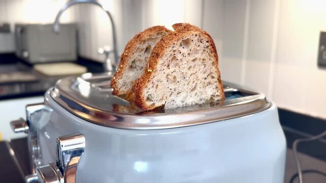 placing four pieces of bread into toaster from side in modern kitchen interior