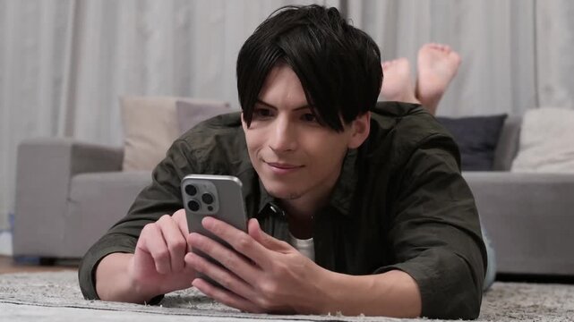 うつ伏せでスマホを見る男性