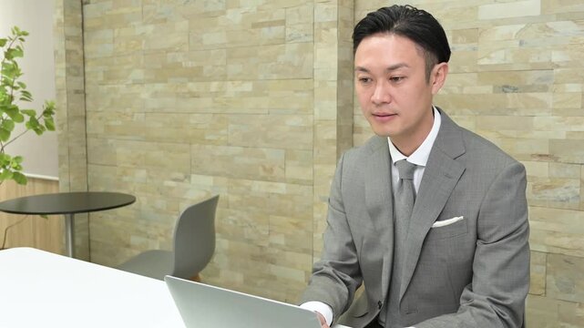 オフィスでパソコン作業をするスーツを着た日本人男性