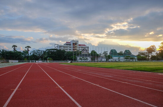 Athletic Track and Skyline View: The vibrant red of an athletic track leads the eye towards a building under a serene sky, capturing a moment of focus and anticipation.