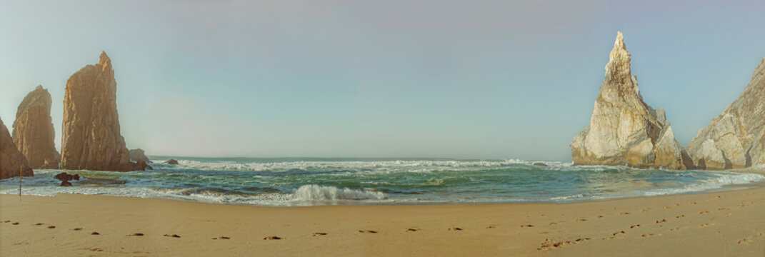 Praia da Ursa, Portugal: Ocean waves crash on sandy beach with rock formations