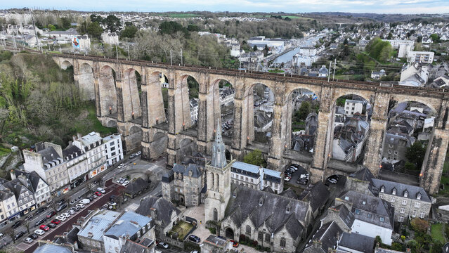 Aerial view of the Eglise Saint-Melaine and the massive stone railway viaduct spanning the valley surrounded by traditional slate-roofed buildings and urban streets Morlaix, Bretagne, France.
