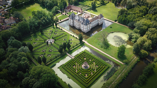 Aerial view of the historic Chateau de Cormatin with its surrounding moat and intricate formal gardens featuring a boxwood maze and geometric patterns in Cormatin, Bourgogne-Franche-Comte, France.