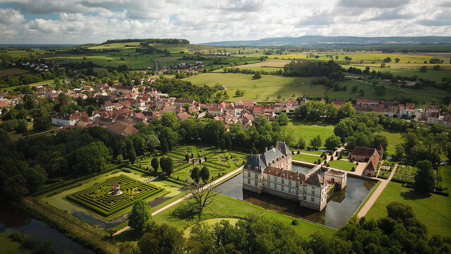 Aerial view of Chateau de Cormatin with its moat, formal gardens and labyrinth surrounded by the village and lush countryside Cormatin, Bourgogne-Franche-Comte, France.