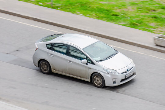 White Toyota Prius third generation car moving in the street in motion. Above front side view