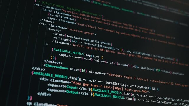 Colorful programming code writes automatically across a dark computer monitor with close-up macro details. The glowing text reveals modern software development happening in real time.