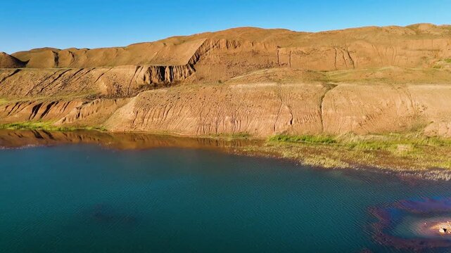 Drone takeoff over massive bauxite aluminum ore dumps and red refractory clay hills in Arkalyk. Footage showcases the scale of technogenic mounds and the unique landscape of the Kostanay region. Perfe