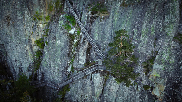 Aerial view of the wooden stairs and walkways of Gorges du Dailley built into a steep rock face with pine trees in Salvan, Valais, Switzerland.