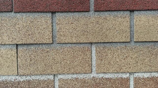 Close-up ondulin cottage roof shingles showing granular texture and mortar lines, weathered earthy tones, asphalt granules