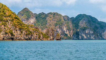 Obraz premium A view towards large and small Karst limestone islets in Ha Long Bay, Vietnam on a bright sunny day